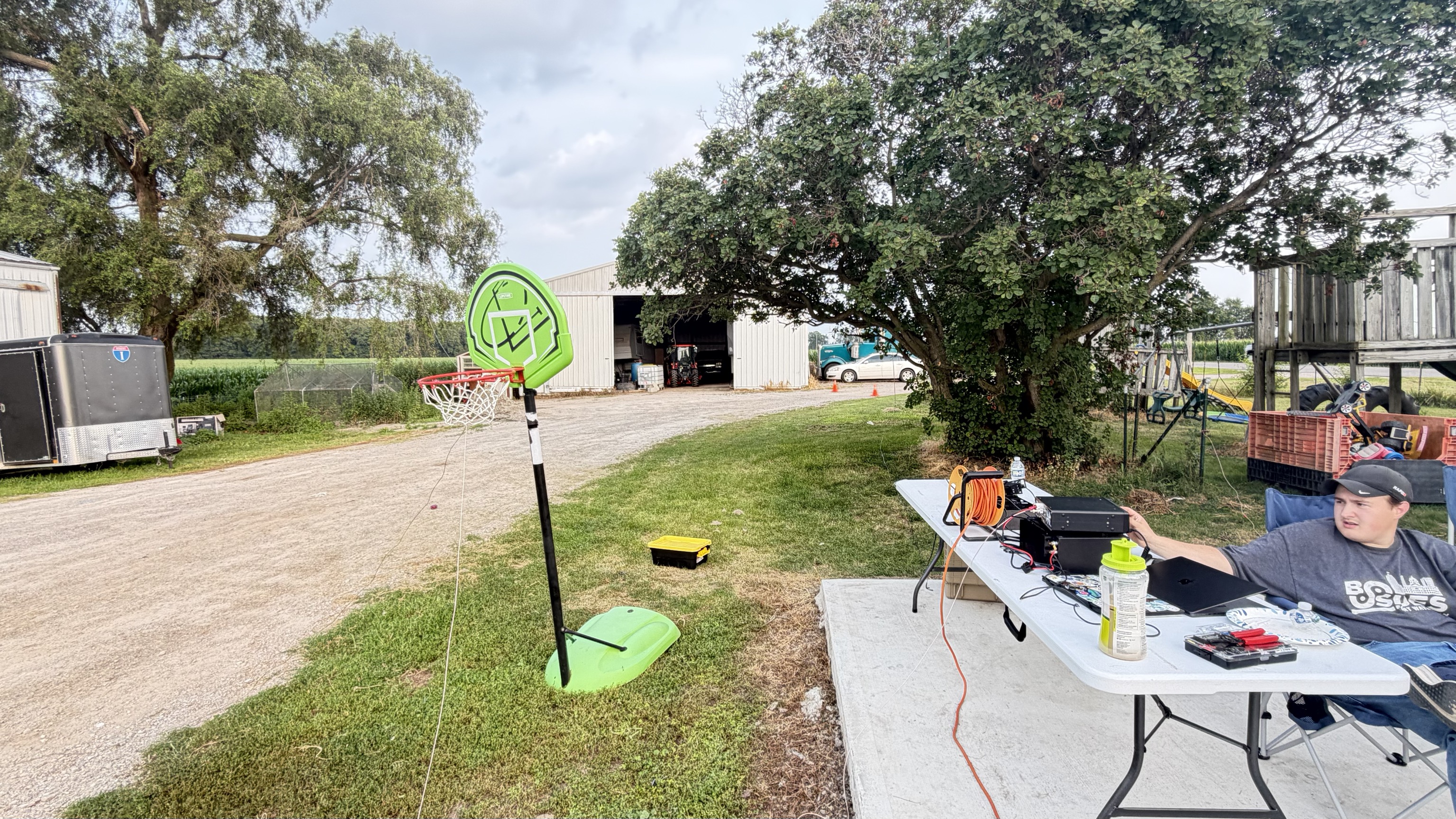 Portable HF station set up under the trees with the end-fed antenna support visible.