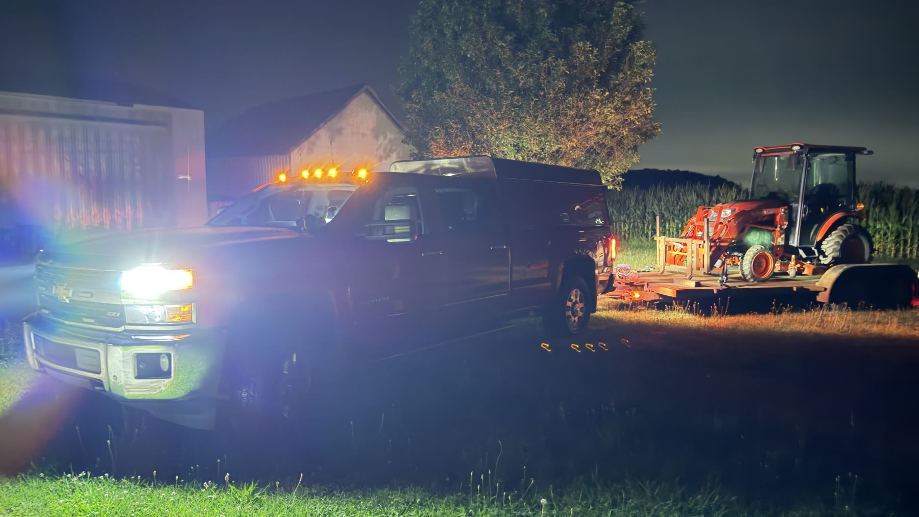 One pickup loaded with tools and towing the tractor before departure.