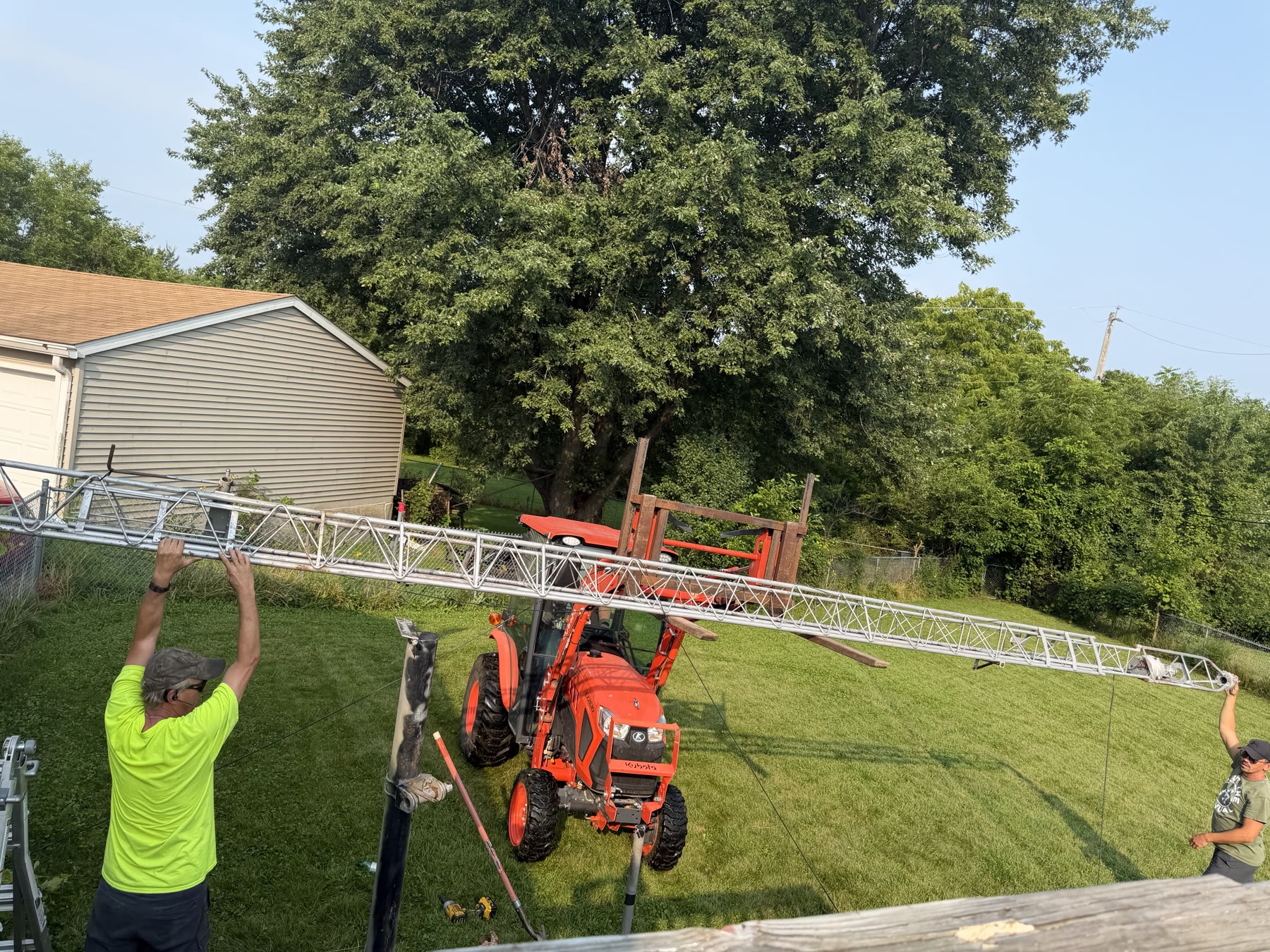 Using the tractor and forks to support the tower while the crew guides it.