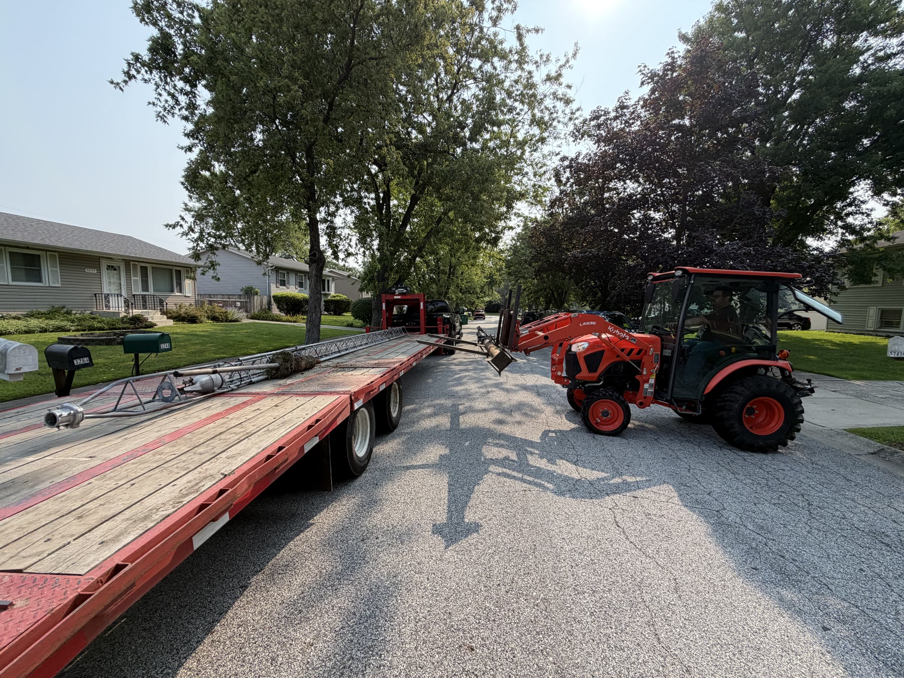 Using the tractor to place the tower onto the 30-foot gooseneck trailer.